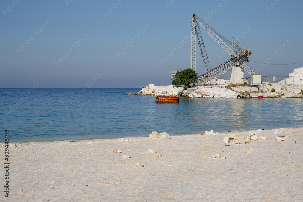 Thassos, Greece, October 02, 2019: Porto Vathy beach on the island of Thassos. White marble mine with conveyor belt on the island