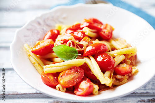 Casarecce pasta with cherry tomatoes and fresh herbs. Close up.