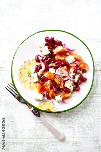 Tasty and easy Salad with Cherry Tomatoes, Feta Cheese, Capers and Kidney Bean. Healthy summer snack. Bright wooden background. Top view. 