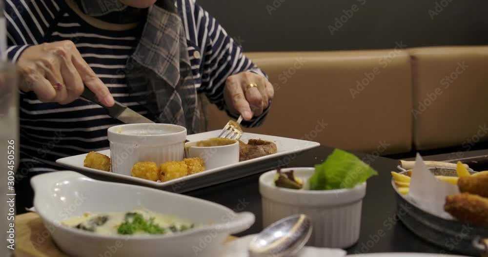 asian woman using knife and folk eating steak. asian woman using knife and folk eating steak.