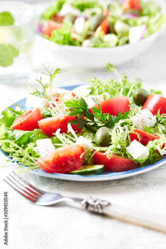 Salad with Green Olives, Tomatoes, Endive and Feta Cheese. Bright Wooden background.  Close up. 