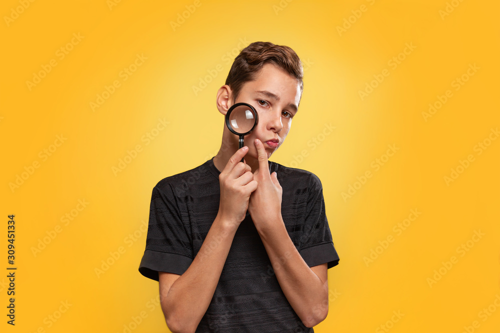 The concept of search. A teenager in a black t-shirt, presses a paw to his cheek. Yellow background. Copy space The concept of search. A teenager in a black t-shirt, presses a paw to his cheek. Yellow background. Copy space