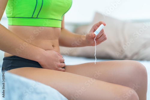 Woman holds cotton female hygienic tampon for protection from bleeding during menstruation. Menstrual hygiene and intimate care. Pain during painful menses period and pms