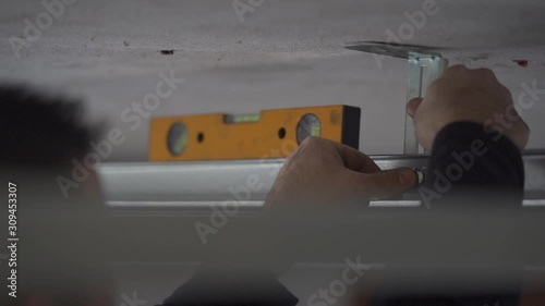 people fixing the top of a garage door or something with a bubble, leveling