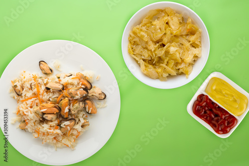 rice with mussels and carrots on awhite plate. rice with mussels and carrots on a colored n background. rice top view. photo