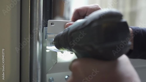 Worker assembling a garage door with a drill, real work atmosphere, close up
