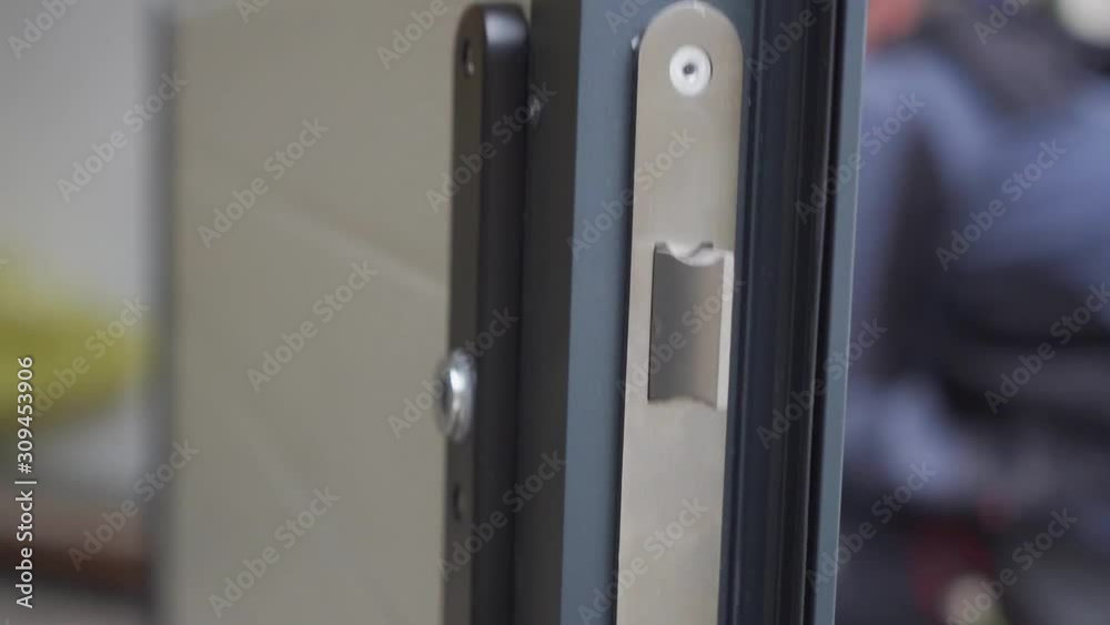 Slow-motion view of a lock with a person in the background who finishes assembling the garage door Slow-motion view of a lock with a person in the background who finishes assembling the garage door