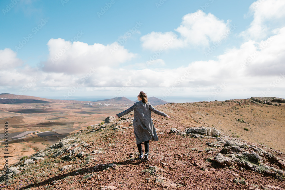 Woman in coat standing in picturesque valley Woman in coat standing in picturesque valley