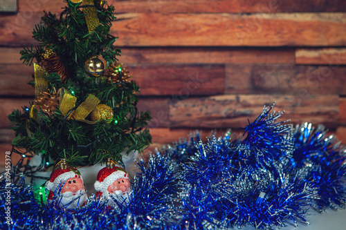 New Year and Christmas-decorated fir tree and beautiful toys with tinsel with snow on a wooden background
