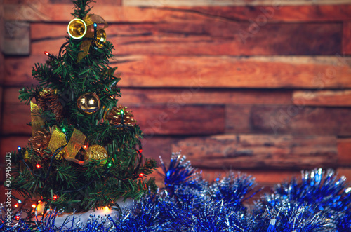 New Year and Christmas-decorated fir tree and beautiful toys with tinsel with snow on a wooden background