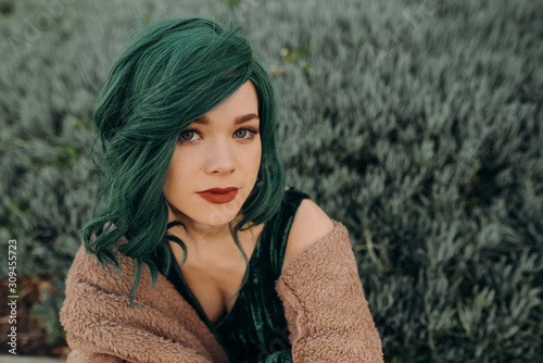 Portrait of young beautiful woman wearing a glamorous green costume wig and red lipstick