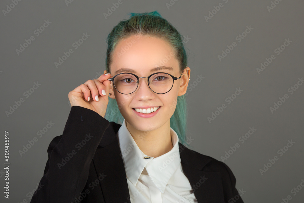 beautiful young woman in glasses and a black suit on a gray background