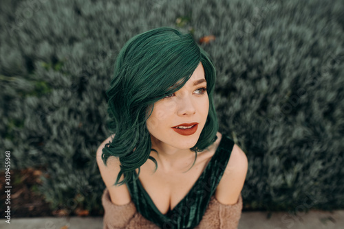 Portrait of young beautiful woman wearing a glamorous green costume wig and red lipstick photo