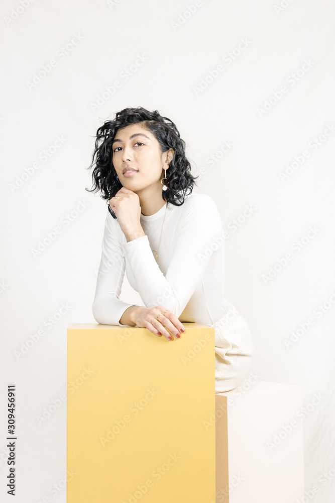 Cute mixed race female modelling for jewelry on colored blocks Cute mixed race female modelling for jewelry on colored blocks