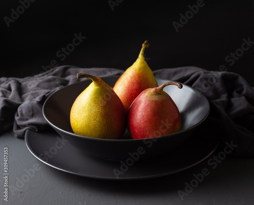 Three fresh seasonal pears on a dark background