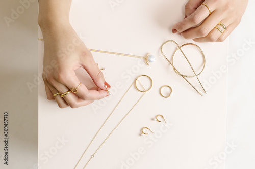 Shot of model hands with gold jewelry on pink wood block photo