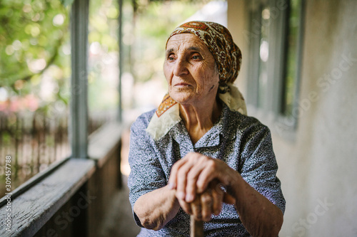 Senior woman in headkerchief on rural house terrace photo