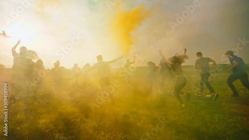 Happy friends girls waving colorful smoke at sunset.