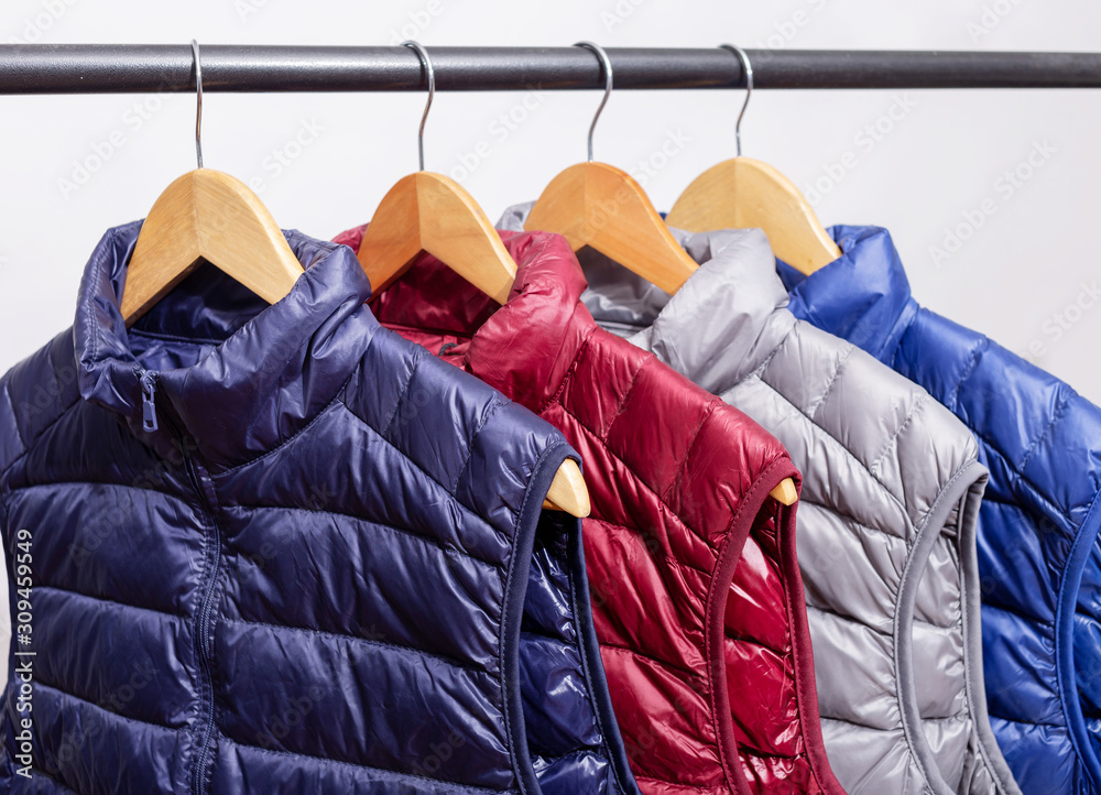 family concept or showroom of down vest jackets hanging on a hanger in the wardrobe