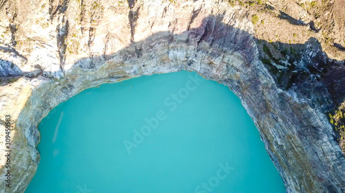 A drone top-down shot of volcano Kelimutu's crater lake in Flores, Indonesia. The lake has a very strong turquoise colour thanks to the minerals in the water. Natural phenomenon