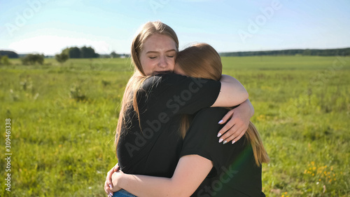 Portrait of hugging two twin sisters in the field on a warm summer day