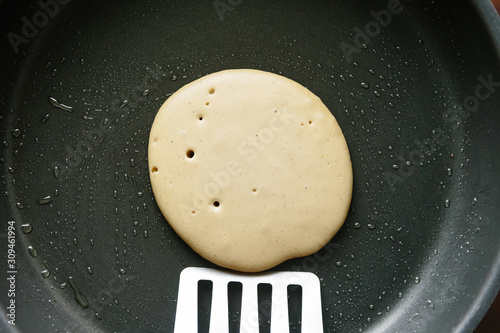 Spatula (or fish slice) turning a vegan pancake with bubbles in photo