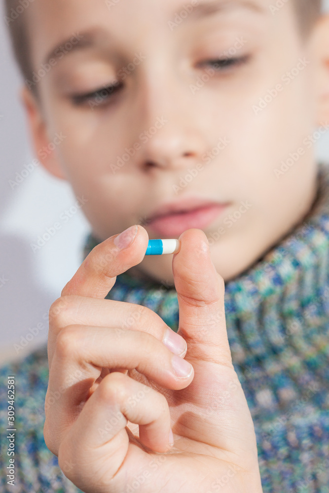 boy is going to drink a pill, child takes medicine, taking antibiotics and pain medications in childhood boy is going to drink a pill, child takes medicine, taking antibiotics and pain medications in childhood