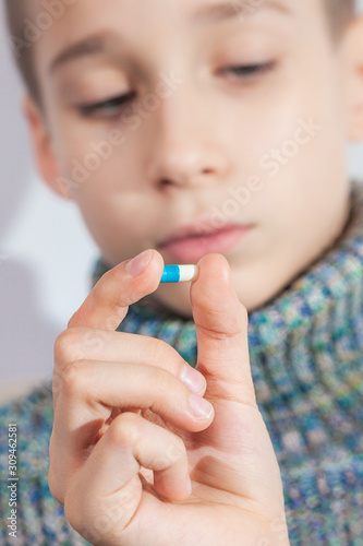 boy is going to drink a pill  child takes medicine  taking antibiotics and pain medications in childhood
