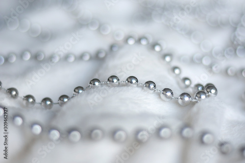 Line of silver beads garland thread chain on a white soft blanket