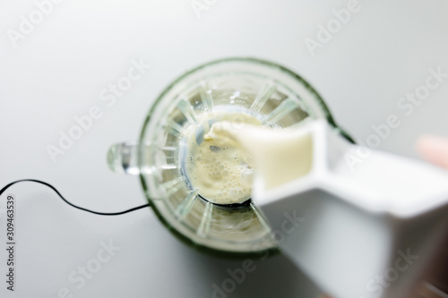 Pouring soya milk into glass blender, from above photo