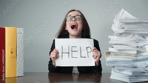 Stressed female office worker sitting at the table among the piles of paperwork and begging for help. Tired screaming office manager overloaded with documentation, nervous office work, stacks of