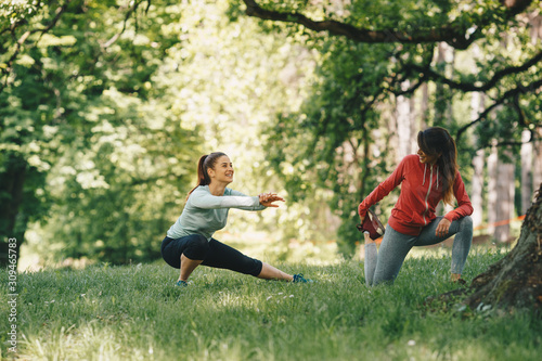 Two attractive young women stretching before running in the park.