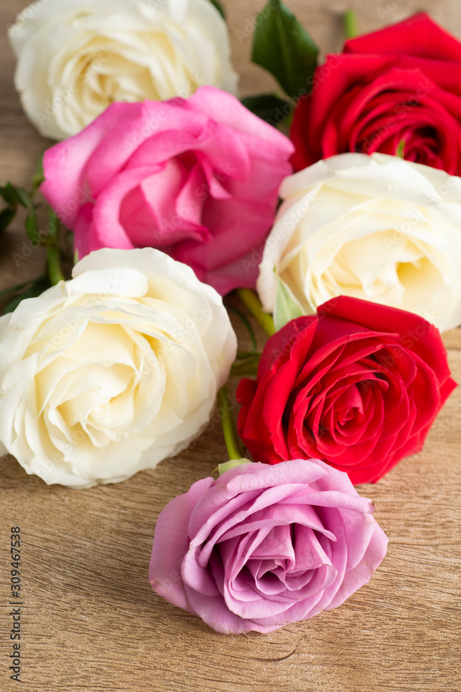 Group of white, red and pink roses over a wooden table Group of white, red and pink roses over a wooden table