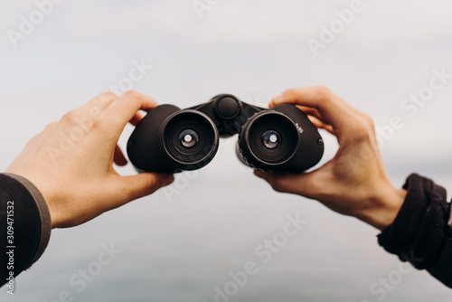 Details of hands holding binoculars looking out toward ocean photo