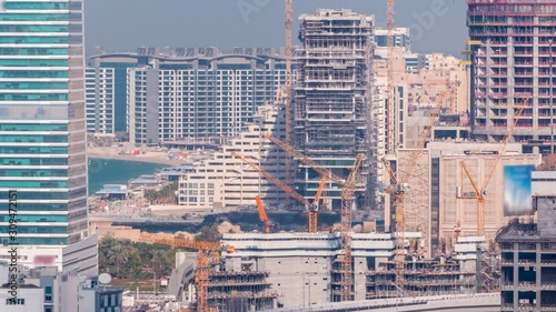 Dubai media city skyscrapers and construction site on palm jumeirah timelapse, Dubai, United Arab Emirates. Aerial view from Greens district with traffic on the road photo