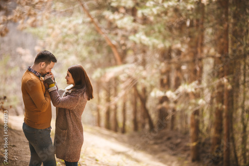 Good-looking young man kissing hands of his beautiful girlfriend while they are standing in the pine forest. © Sanja