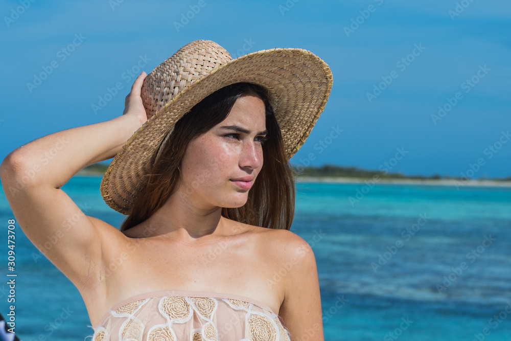 Portrait of happy sexy caucasian woman wearing beach hat smiling at blue sea.