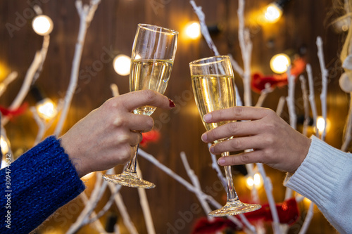 woman hands cheers with two glasses of champagne holidays festive atmosphere concept wallpaper with illumination lights