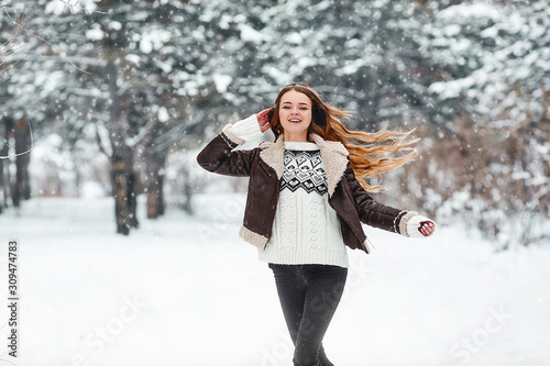 Happy young woman engoing winter, frosty day. Playing with snow on winter holidays. Woman Walk in winter forest.