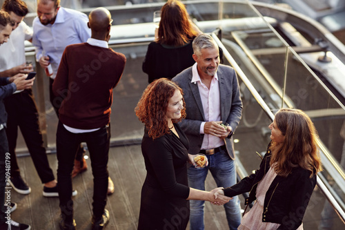 High angle view of businesswoman doing handshake and greeting while partying with coworkers after work on terrace photo
