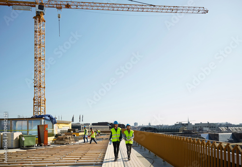 Female coworkers walking at construction site against clear sky