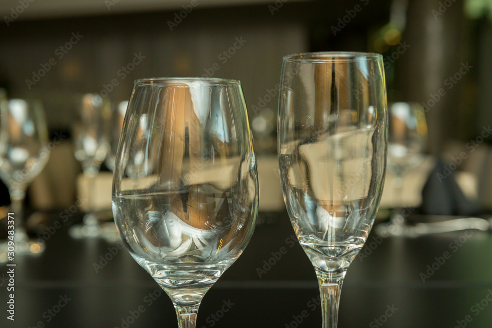 Side view of two different empty glass cups on a black table. Empty wine glass on a gray background. Side view of two different empty glass cups on a black table. Empty wine glass on a gray background.