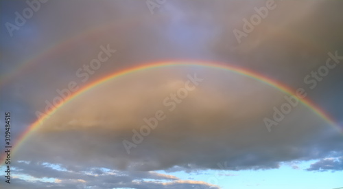 Full double rainbow in the sky against the background of clouds
