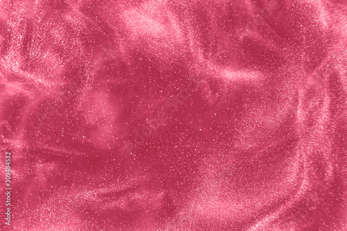Abstract elegant, detailed pink glitter particles flow with shallow depth of field underwater. Holiday magic shimmering luxury background. Festive sparkles and lights. de-focused.