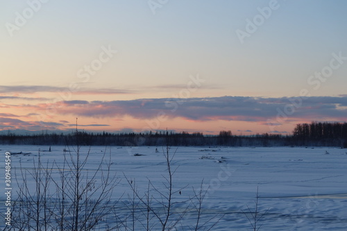 Sunrise colored sky over frozen river