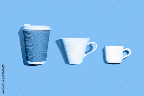 Coffee pattern of white ceramic and blue paper cup for coffee on classic blue background.