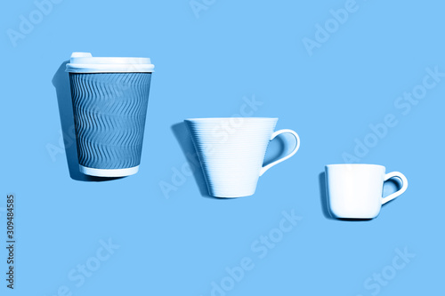 Coffee pattern of white ceramic and blue paper cup for coffee on classic blue background.