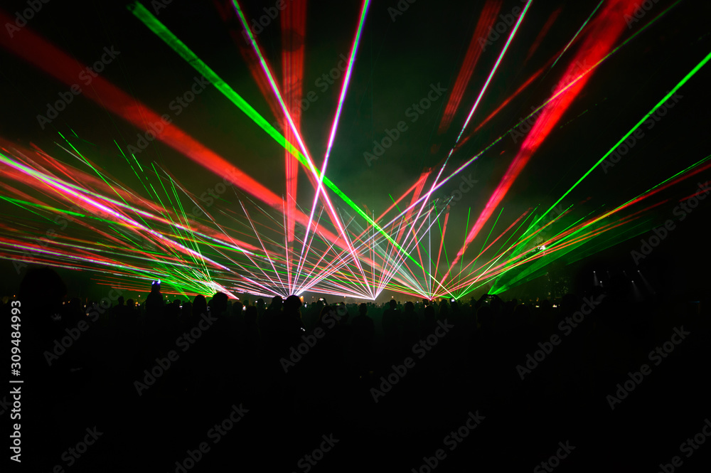 People bathed in fog and laser light, laser show.
