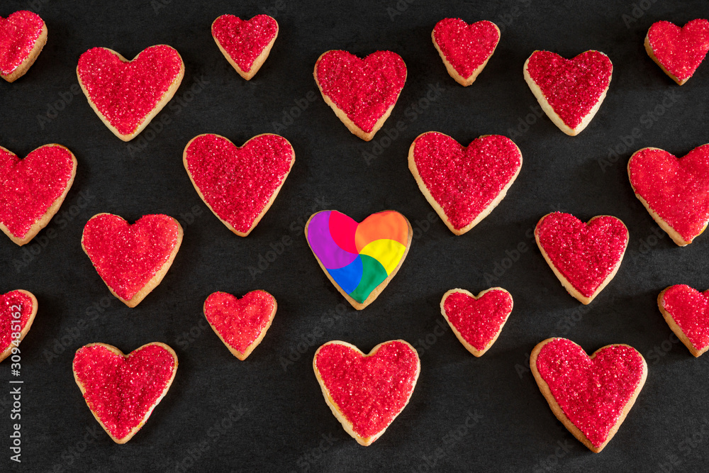 Red and rainbow heart shaped cookies on black background, distinction concept, love symbol, valentine's day pattern