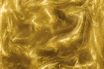 Abstract elegant, detailed gold glitter particles flow with shallow depth of field underwater. Holiday magic shimmering luxury background. Festive sparkles and lights. de-focused.